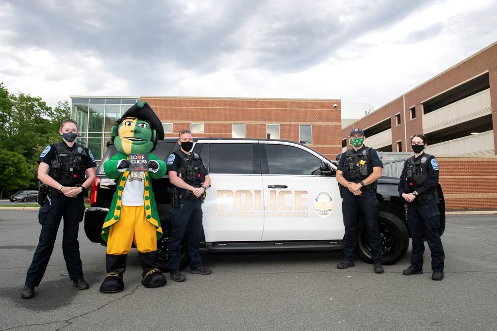 Four members of the Mason Police force stand in front of a campus patrol car with the Patriot.