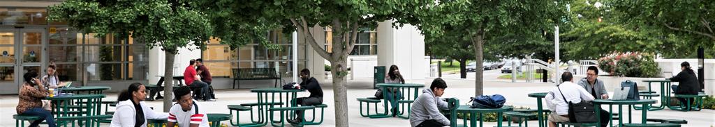 Students sit in the plaza of Mason Square at picnic tables.