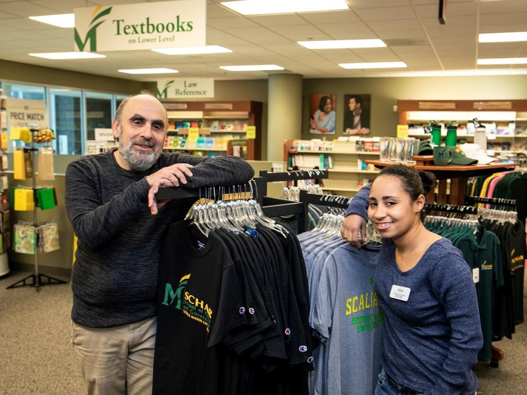 Two bookstore staff members stand near a clothing rack inside the Mason Square Bookstore.