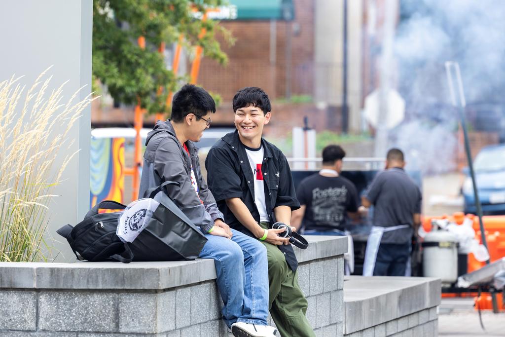Two students sit together on the plaza